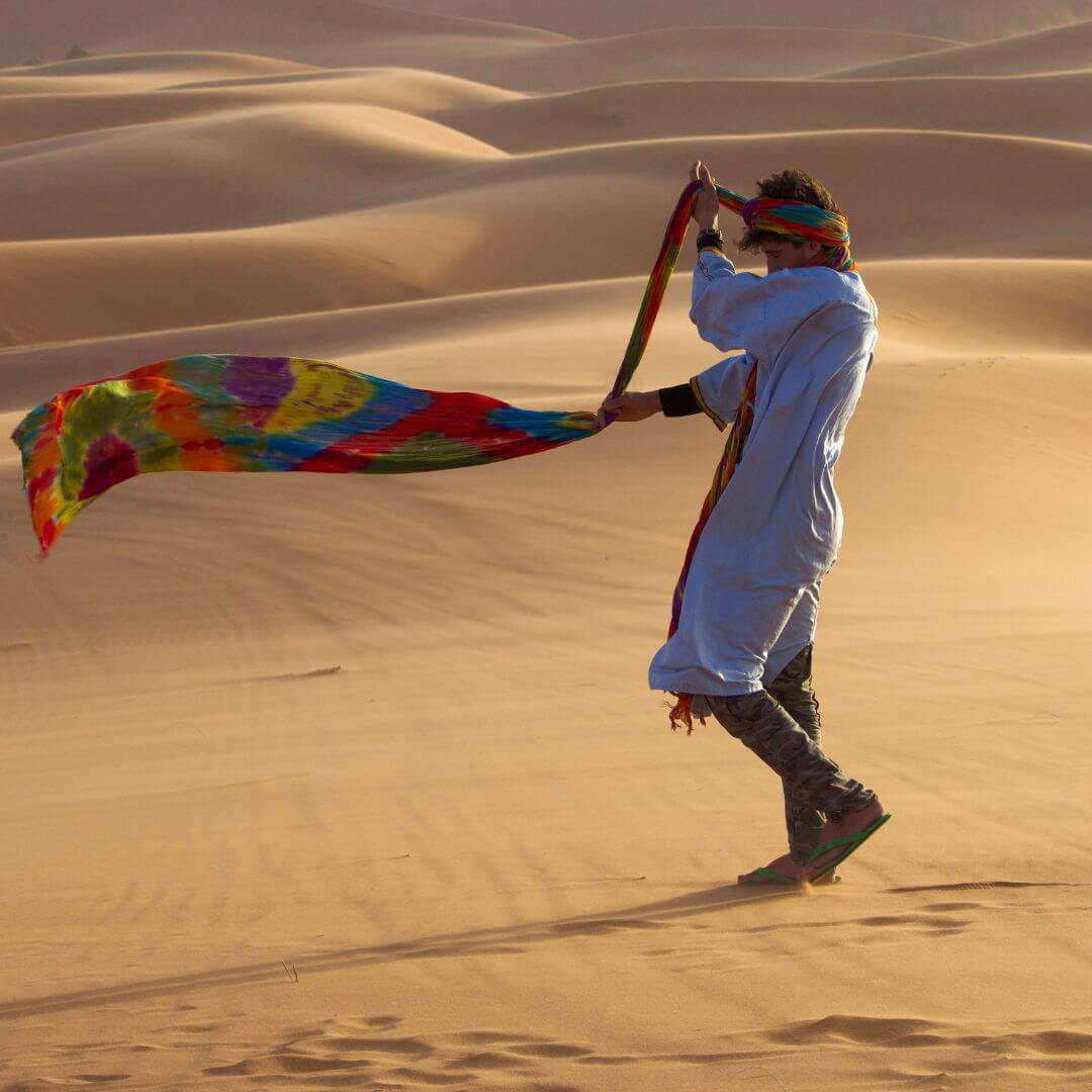 صورة لمرشد سياحي محلي يرتدي الملابس التقليدية الصحراوية وهو يشرح تفاصيل الرحلة لمجموعة من السياح المهتمين